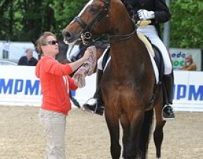 Isabell Werth helps her assistant trainer Matthias Bouten on Flatley