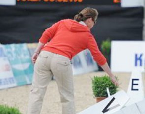 Isabell Werth straightens the arena after the wind knocked over some letters