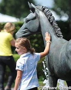 A young horse fan posing with one of the bronze sculptures