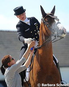 Isabell Werth's groom prepares Bella Rose with a final bit of fly spray before the mare enters the ring