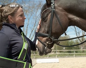 Dorothee Schneider with her arm in a sling, patting Faustus :: Photo SWR sport
