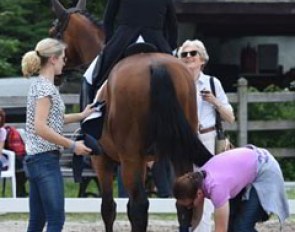 Isabell Werth talking to her sponsor Madeleine Winter-Schulze as Beatrice Buchwald and a groom take care of rider and horse