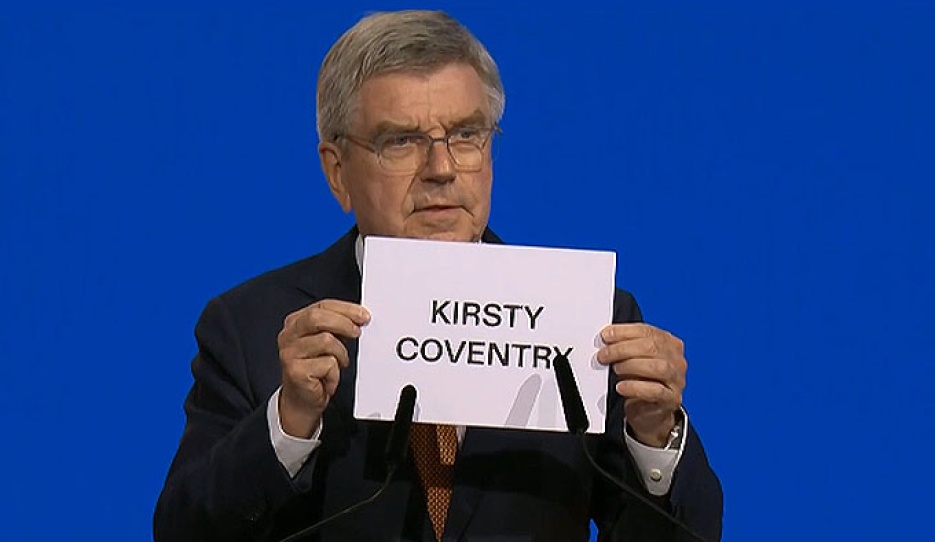 IOC president Thomas Bach shows the name of the winner of the secret ballot at the 144th IOC Session being held in Costa Navarino