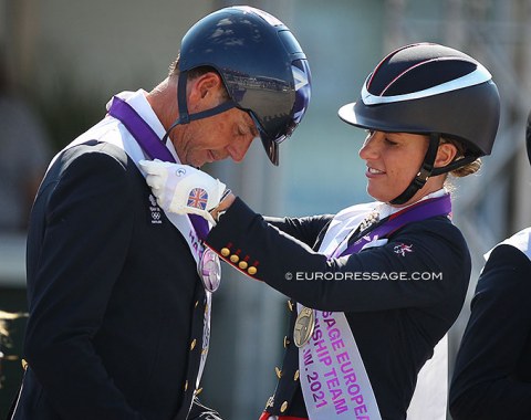 Charlotte Dujardin hanging the silver medal round Carl Hester's neck