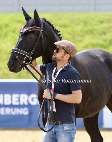 Former Austrian Young Rider Christopher Erdmann holds the horse of his student, Austrian Julia Sciancalepore, during the prize-giving in Grade 1
