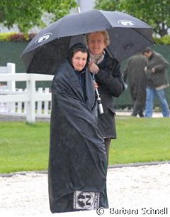 Werth's sponsor Madeleine Winter-Schulze and groom Anna Kleniuk sheltering from the pouring rain.