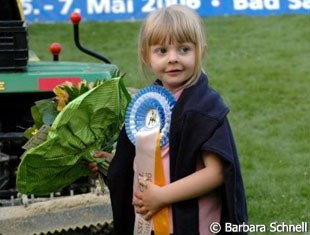 Ann Kathrin Linsenhoff's daughter Marie with her brother's winner's ribbon.