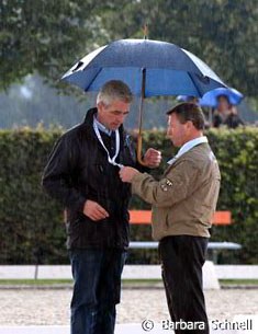 While Holger Schmezer did have his striking black-red-golden umbrella with him while the sun was shining, he left it in the car just before it started to pour. Junior riders' trainer Hans-Heinrich Meyer zu Strohen helps him out.