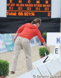 Isabell Werth straightens the arena after the wind knocked over some letters