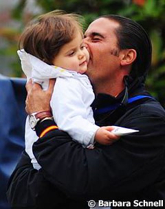 Jose Antonio Garcia Mena, who has been helping Isabell Werth to put the piaffe on her horses, cuddles with his child