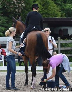 Isabell Werth talking to her sponsor Madeleine Winter-Schulze as Beatrice Buchwald and a groom take care of rider and horse