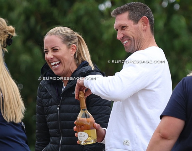 Charlotte Dujardin and Dean Golding celebrating student Annabella Pidgley's silver medal at the 2022 European Junior Championships in Hartpury in July. Golding opening the bottle for the champagne shower :: Photo © Astrid Appels